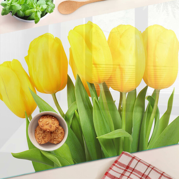 Üveg vágódeszka fényképpel Sárga tulipánok zöld háttér előtt