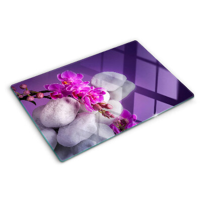 Üveg vágódeszka fényképpel Orchidea virágok kövek hátterében
