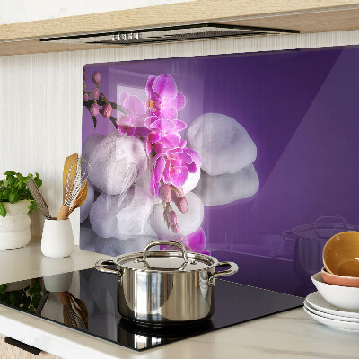 Üveg vágódeszka fényképpel Orchidea virágok kövek hátterében