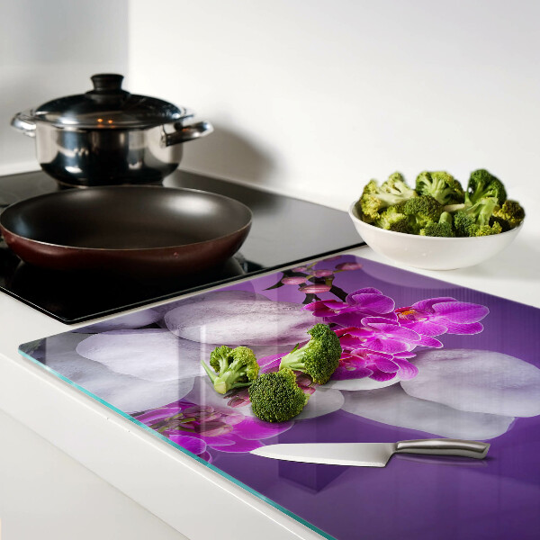 Üveg vágódeszka fényképpel Orchidea virágok kövek hátterében