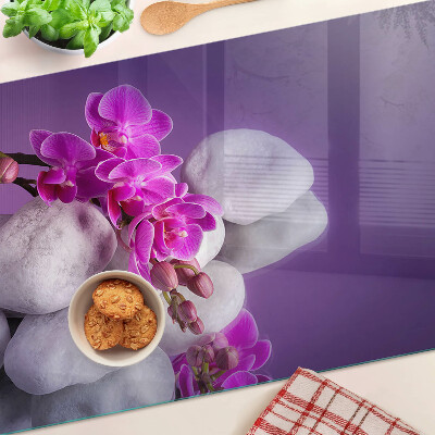Üveg vágódeszka fényképpel Orchidea virágok kövek hátterében