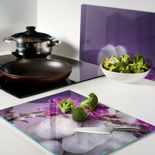Üveg vágódeszka fényképpel Orchidea virágok kövek hátterében