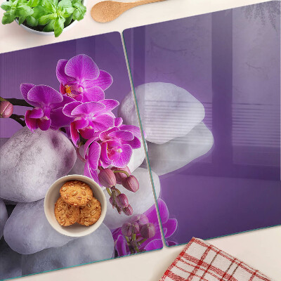Üveg vágódeszka fényképpel Orchidea virágok kövek hátterében