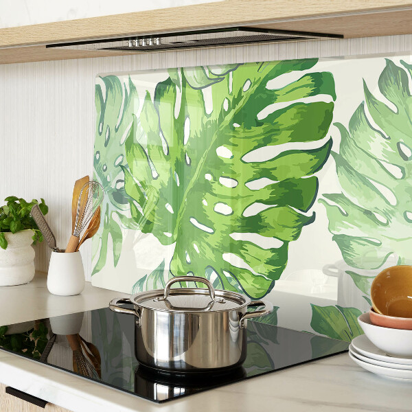 Üveg vágódeszka fényképpel Monstera levelek világos háttér előtt