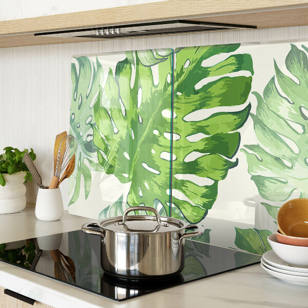 Üveg vágódeszka fényképpel Monstera levelek világos háttér előtt