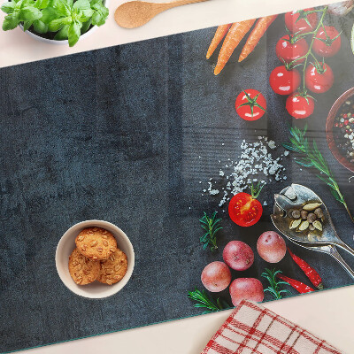 Edzett üveg vágódeszka Zöldségek és fűszerek sötét háttér előtt